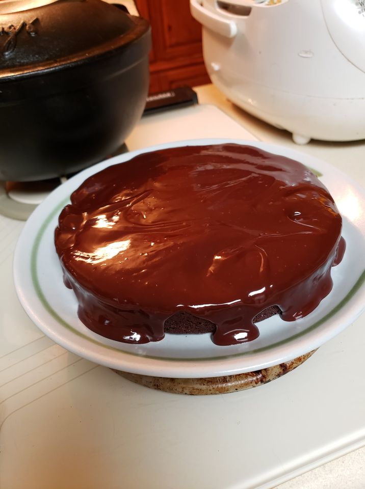 An image of a one-layer flourless chocolate cake with freshly made ganache covering the top and oozing down the sides.